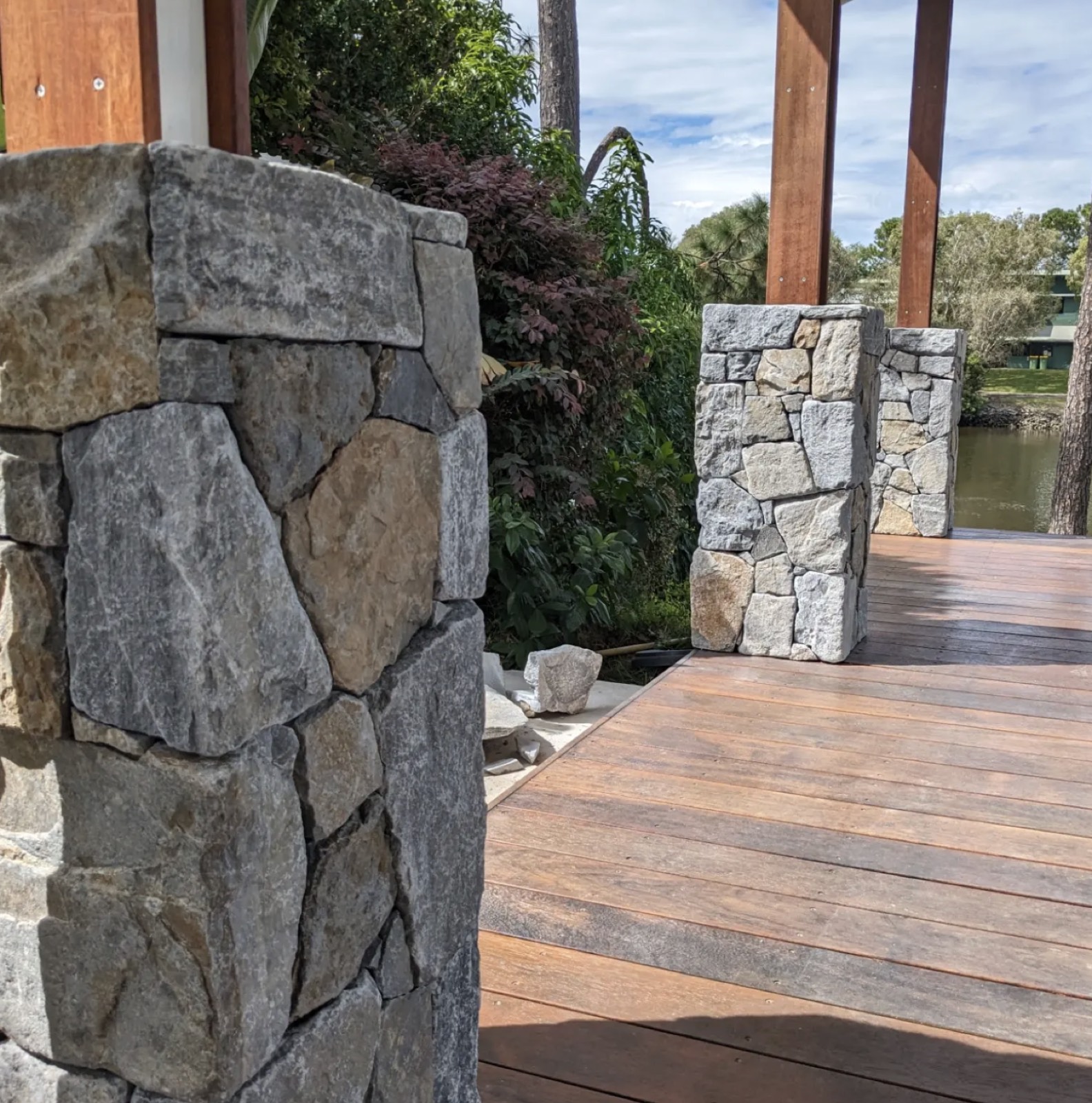Natural stone clad pillars on a hardwood deck by the water