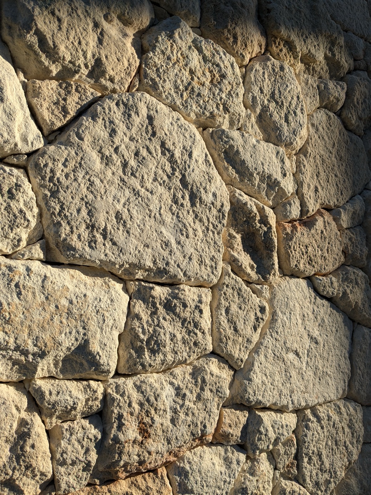 Close-up of hand-laid sandstone wall in golden evening light